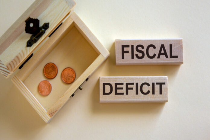 Concept words 'fiscal deficit' on blocks on a beautiful white background, small chest with coins.